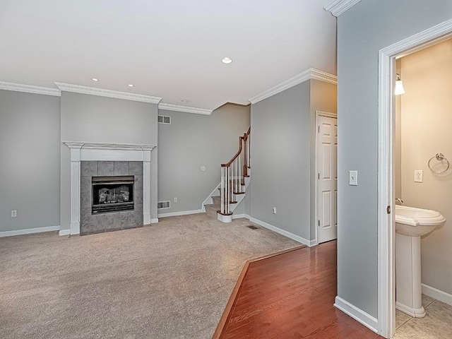 unfurnished living room with ornamental molding, carpet flooring, sink, and a tile fireplace