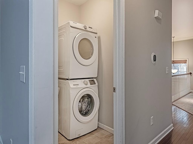 laundry area featuring stacked washer and dryer and light hardwood / wood-style flooring