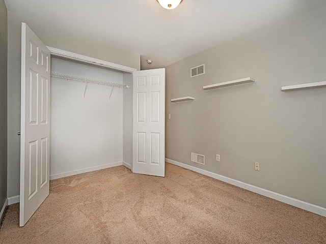 unfurnished bedroom with a closet and light carpet