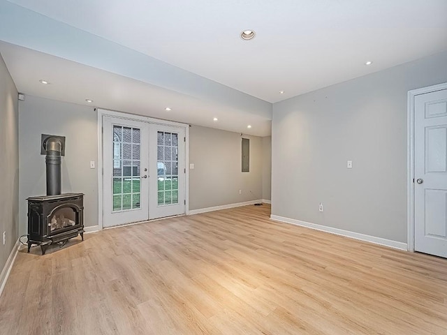 unfurnished living room featuring light hardwood / wood-style floors, french doors, and a wood stove