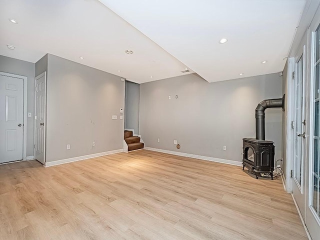 unfurnished living room featuring a wood stove and light wood-type flooring