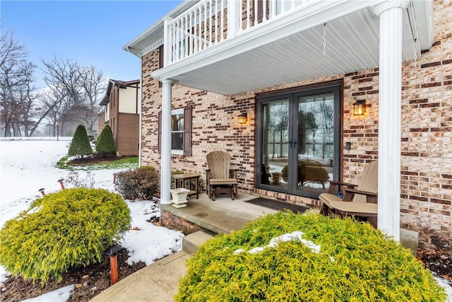 snow covered patio featuring french doors and a balcony