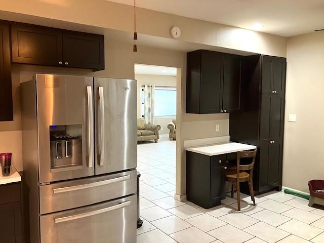 kitchen with stainless steel refrigerator with ice dispenser, dark brown cabinetry, and light tile patterned flooring