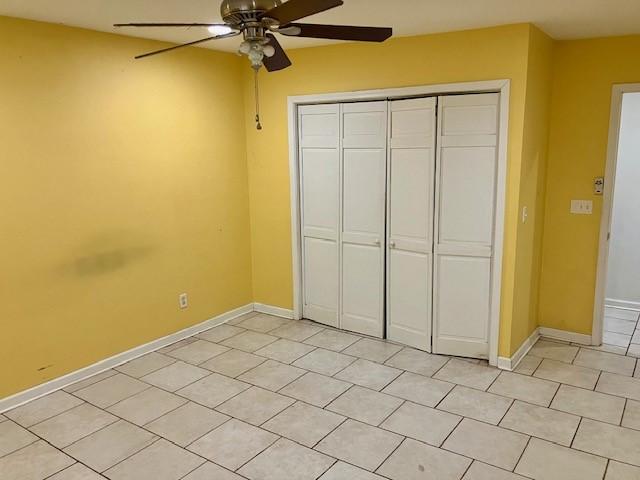 unfurnished bedroom featuring ceiling fan and a closet