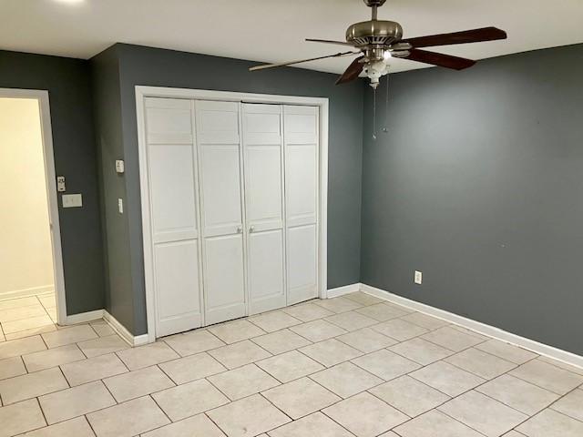 unfurnished bedroom with light tile patterned floors, ceiling fan, and a closet