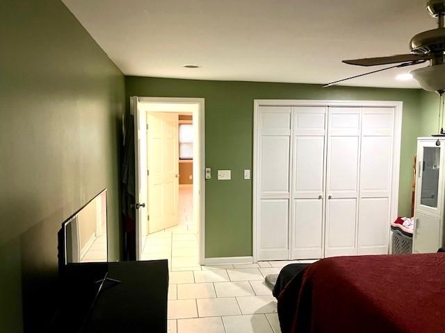 tiled bedroom with ceiling fan and a closet