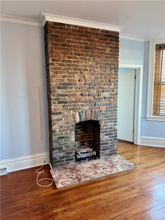 details with crown molding, wood-type flooring, and a large fireplace