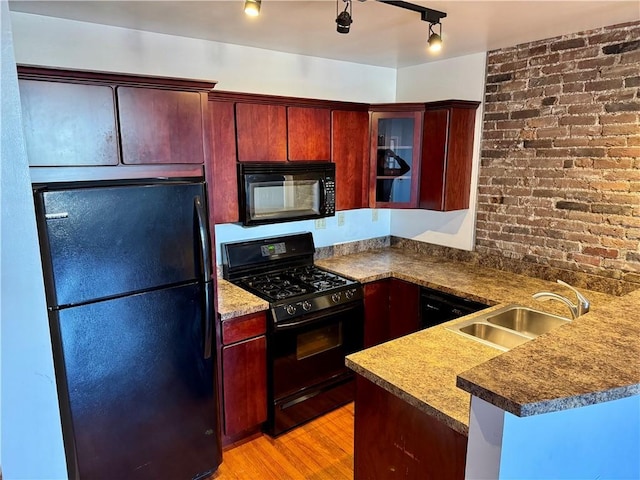 kitchen with sink, kitchen peninsula, light hardwood / wood-style floors, and black appliances