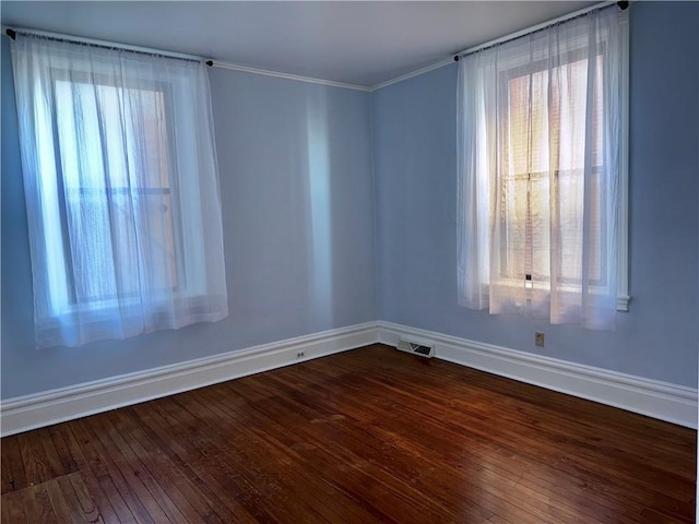 empty room with ornamental molding, plenty of natural light, and hardwood / wood-style floors