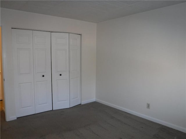 unfurnished bedroom featuring dark carpet and a closet