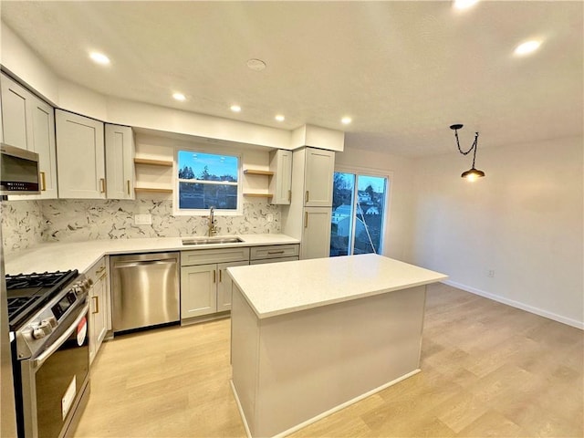 kitchen with sink, light hardwood / wood-style flooring, hanging light fixtures, stainless steel appliances, and a center island