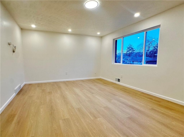 empty room with a textured ceiling and light wood-type flooring