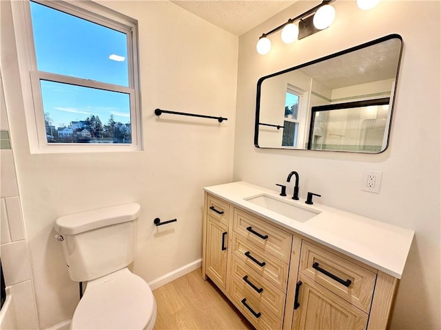 bathroom with an enclosed shower, vanity, hardwood / wood-style flooring, and toilet