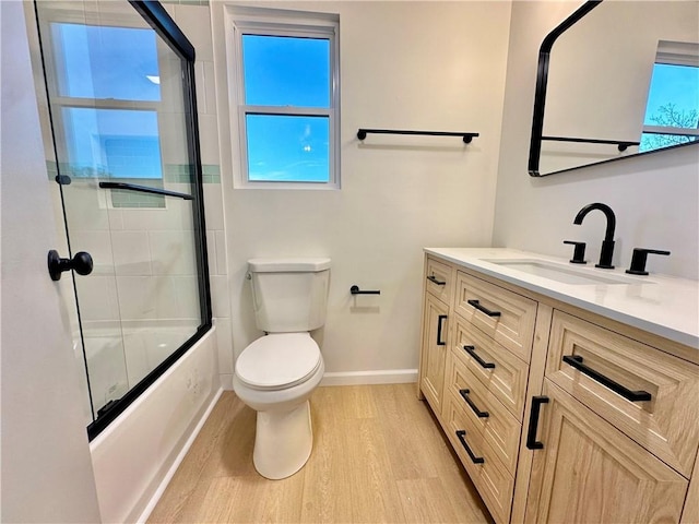 full bathroom featuring toilet, vanity, shower / bath combination with glass door, and hardwood / wood-style floors