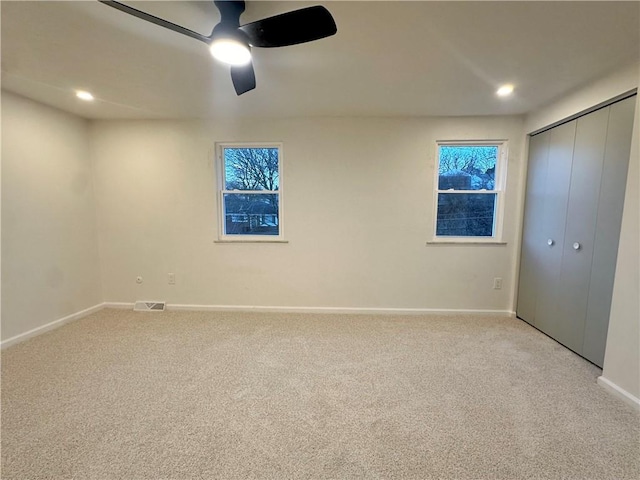 unfurnished bedroom with ceiling fan, a closet, and light carpet