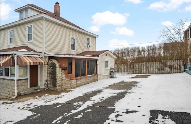 snow covered property with a chimney and fence