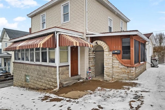 exterior space with stone siding and a sunroom