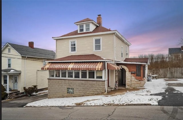 american foursquare style home with a shingled roof, a chimney, and fence