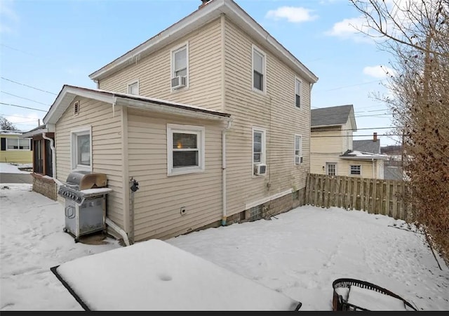 snow covered rear of property featuring fence