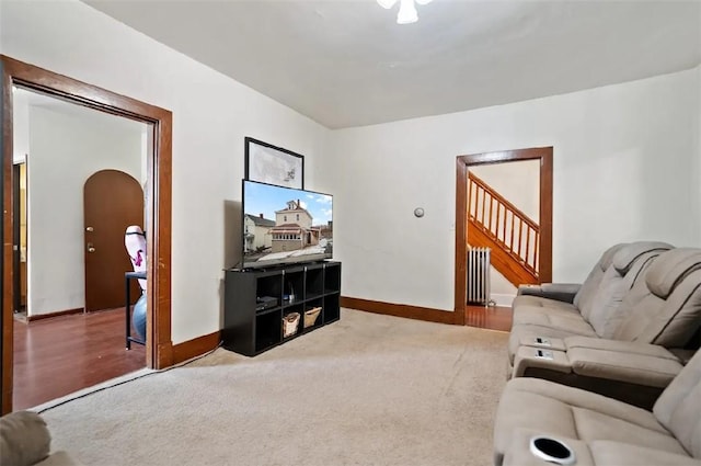 living room featuring carpet floors, arched walkways, radiator, and baseboards