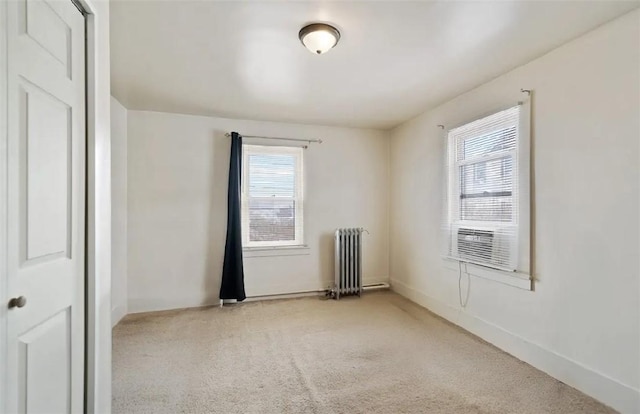 empty room featuring carpet, radiator, cooling unit, and plenty of natural light