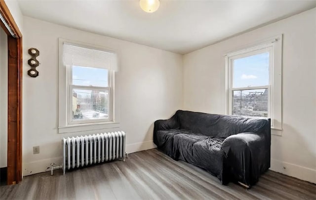 sitting room with radiator heating unit, wood finished floors, and baseboards