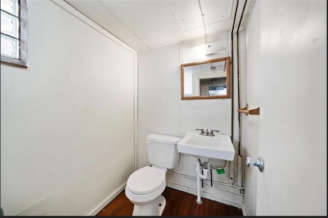 half bathroom featuring baseboards, toilet, and wood finished floors