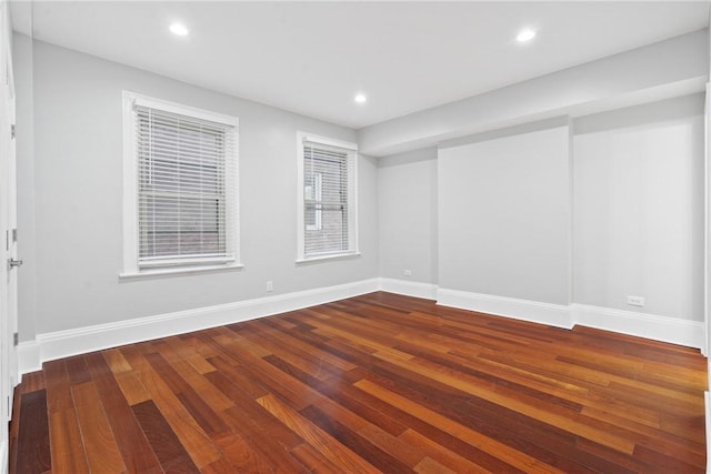 spare room with baseboards, wood finished floors, and recessed lighting