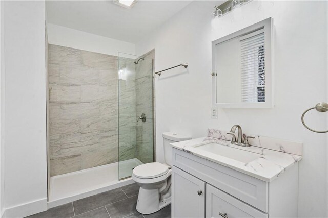 bathroom with vanity, a tile shower, tile patterned floors, and toilet