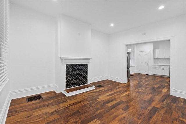 unfurnished living room with a fireplace, baseboards, dark wood-type flooring, and recessed lighting