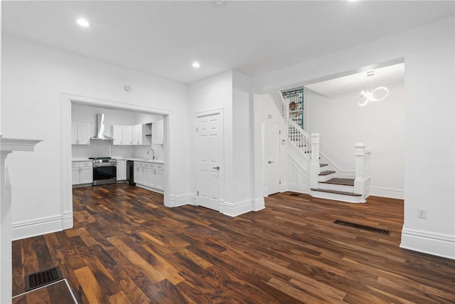 unfurnished living room featuring dark hardwood / wood-style floors, a chandelier, and sink