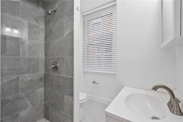 bathroom with vanity, toilet, and tiled shower