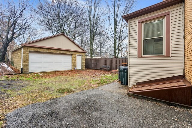 view of property exterior with a garage, an outdoor structure, and central AC