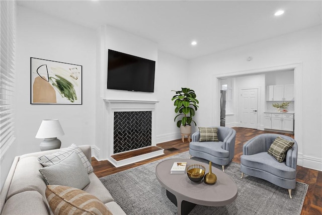 living room featuring baseboards, a fireplace, dark wood finished floors, and recessed lighting