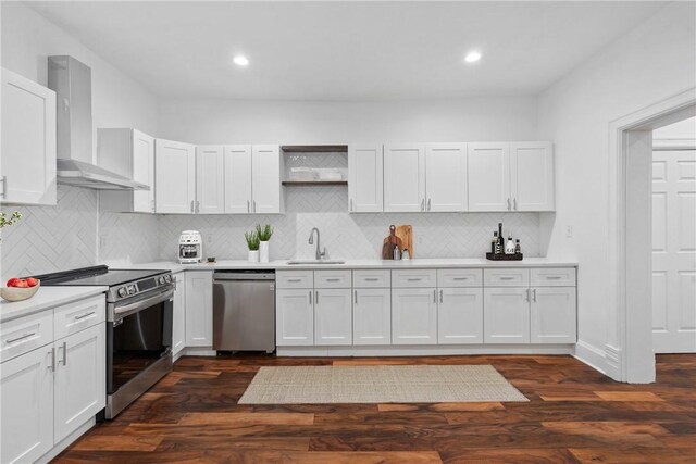 kitchen with white cabinetry, sink, stainless steel appliances, dark wood-type flooring, and wall chimney range hood