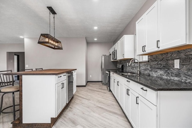 kitchen featuring pendant lighting, light hardwood / wood-style flooring, white cabinetry, stainless steel appliances, and a kitchen bar