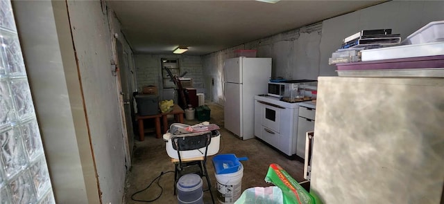 kitchen featuring white refrigerator, white cabinets, and concrete floors