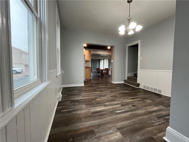 spare room with an inviting chandelier and dark hardwood / wood-style floors