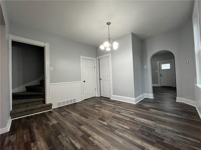 unfurnished dining area with a notable chandelier and dark wood-type flooring