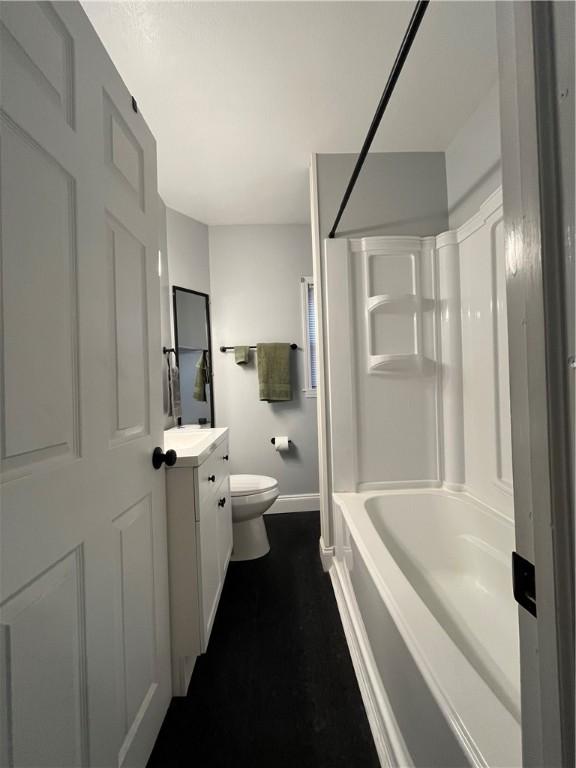 bathroom featuring baseboards, toilet, shower / tub combination, and vanity
