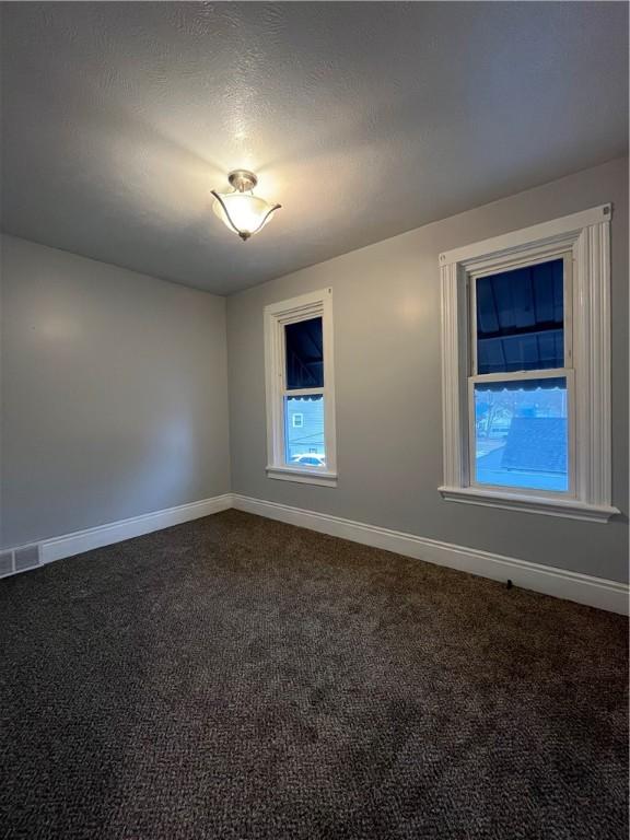 unfurnished room featuring baseboards and dark carpet