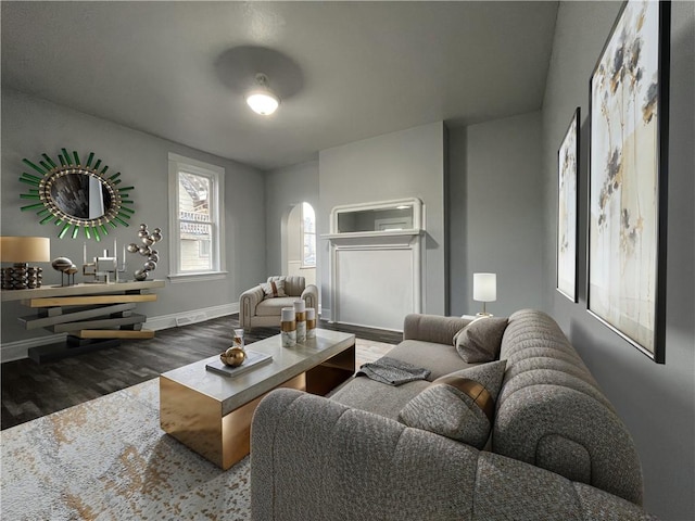 living area featuring wood finished floors, baseboards, visible vents, and arched walkways