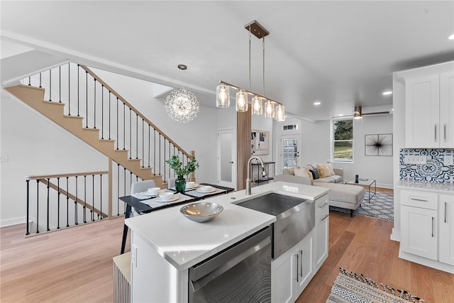 kitchen with sink, white cabinetry, decorative light fixtures, an island with sink, and light hardwood / wood-style floors