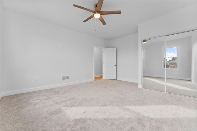 unfurnished bedroom with ceiling fan, light colored carpet, and a closet