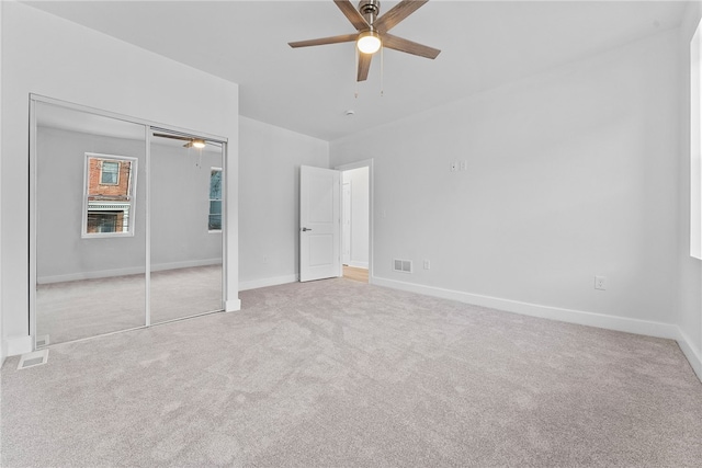 unfurnished bedroom with ceiling fan, light colored carpet, and a closet