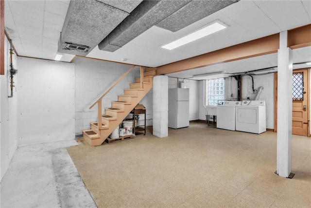 basement featuring white fridge and washing machine and clothes dryer