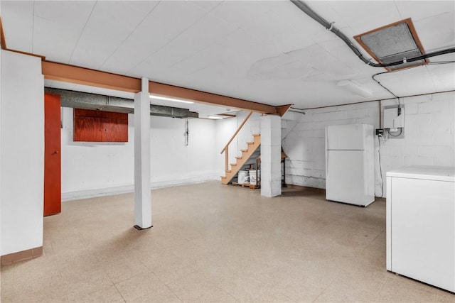 basement featuring white refrigerator and washer / dryer