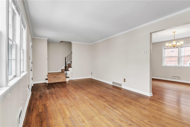 empty room with ornamental molding, wood-type flooring, and a notable chandelier