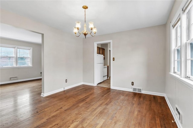 unfurnished room with hardwood / wood-style flooring and a chandelier