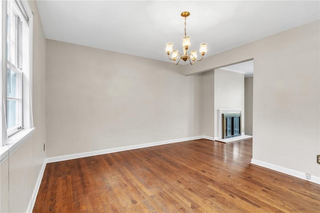 empty room with wood-type flooring and a notable chandelier